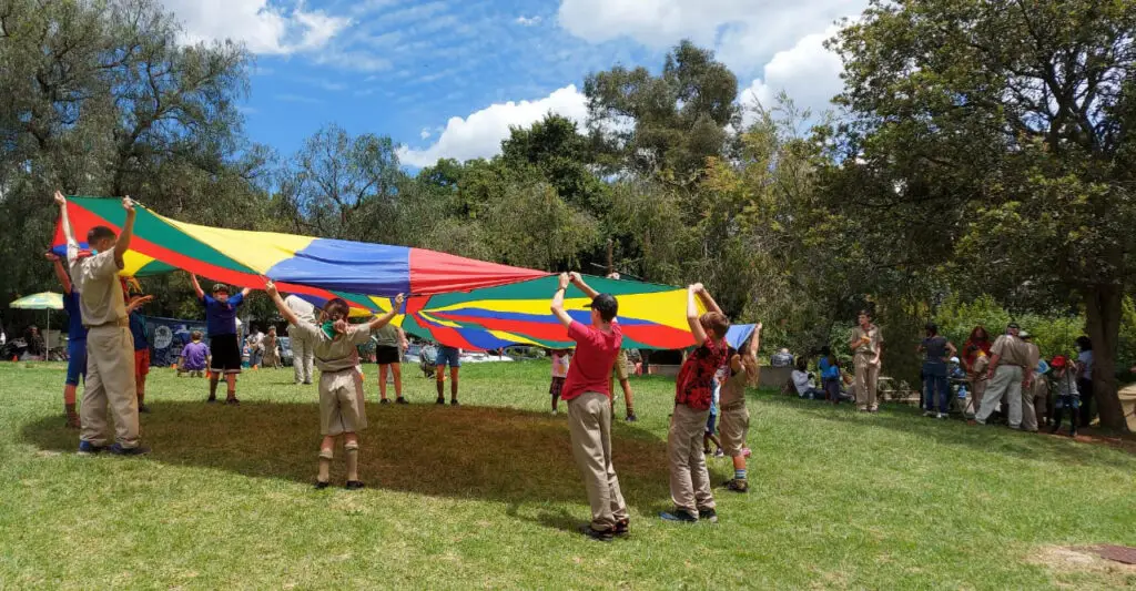 About Randpark Ridge Scout Group picture of scouts in circle holding large flag